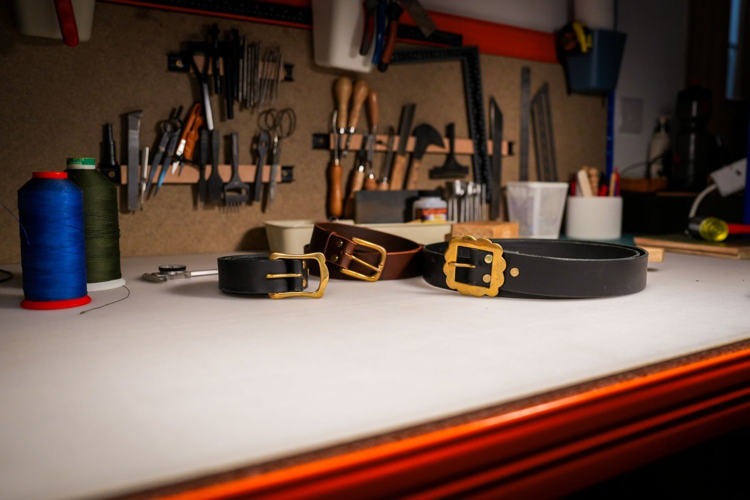 The workshop bench with finished belts, thread and leatherworking tools